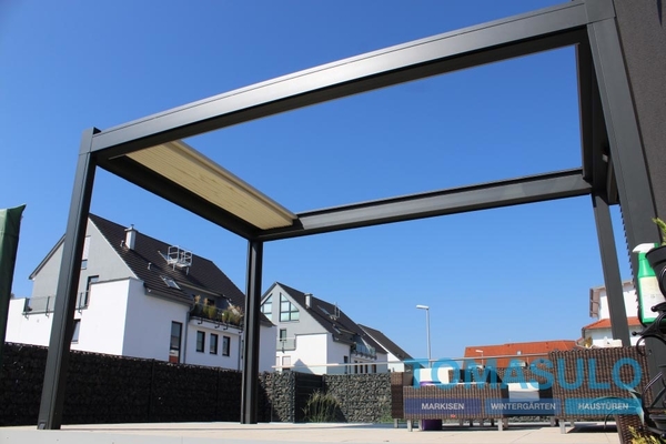 Moderne Aluminium-Terrassenüberdachung vor Einfamilienhäusern bei klarem Himmel.
