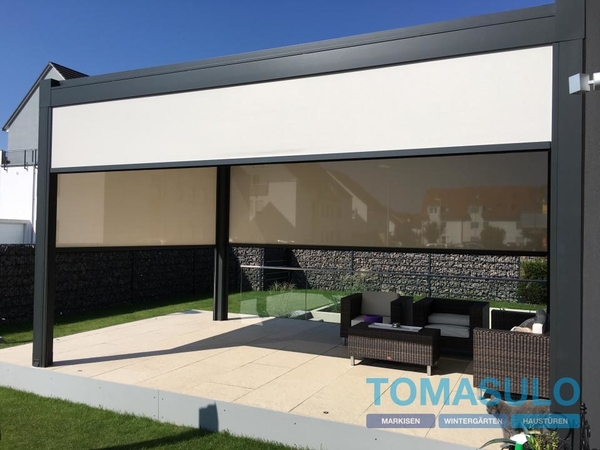 Moderne Terrassenüberdachung mit Markise und Gartenmöbeln auf gepflegtem Rasen.