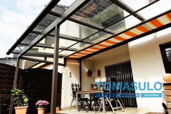 Überdachte Terrasse mit Glasdach und Markise, moderne Terrassenüberdachung am Haus.